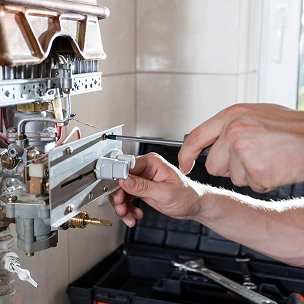 Un plombier répare un chauffe-eau dans une cuisine.